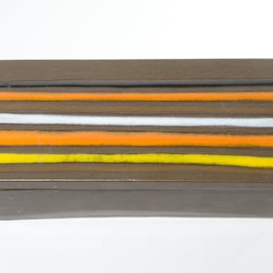 May include: A rectangular box with a brown lid and a striped design. The lid has five horizontal stripes in yellow, orange, white, orange, and black.