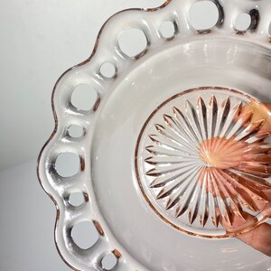 Pode incluir: Um prato de sobremesa de vidro rosa vintage com uma borda festonada e um design de vidro cortado no centro.