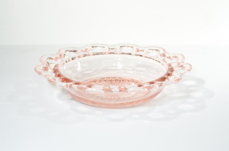 Pode incluir: Uma tigela de vidro rosa com uma borda festonada. A tigela tem um padr&atilde;o floral delicado no fundo.