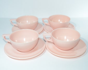 Puede incluir: Juego de cuatro tazas de té y platillos rosas. Las tazas y los platillos están hechos de un material liso y brillante.