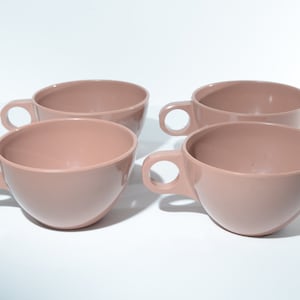 May include: Set of four brown ceramic teacups with rounded handles.