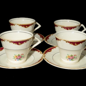 Puede incluir: Juego de cuatro tazas y platillos vintage. Las tazas y platillos de porcelana blanca presentan un diseño de borde burdeos y dorado. Cada platillo tiene un ramo floral en el centro.