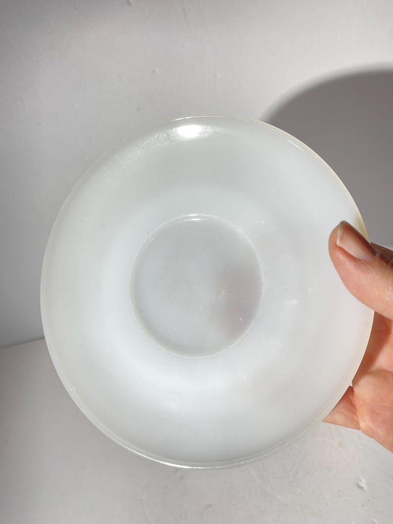 Może przedstawiać: Biały ceramiczny spodek o gładkim, błyszczącym wykończeniu. Spodek jest okrągły i ma lekko uniesiony brzeg.
