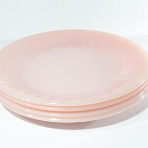 Op de afbeelding: Vier roze glazen borden gestapeld op elkaar. De borden hebben een licht gegolfde rand.