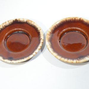 Könnte beinhalten: Zwei braune und weiße Untertassen aus Keramik mit glasierter Oberfläche.