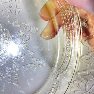 May include: A clear glass plate with a gold rim and a delicate floral pattern. The plate has a vintage look and is perfect for serving desserts or appetizers.