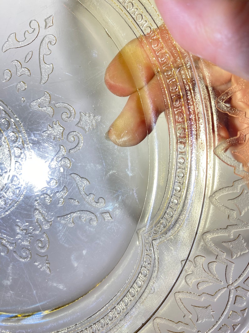 May include: A clear glass plate with a gold rim and a delicate floral pattern. The plate has a vintage look and is perfect for serving desserts or appetizers.