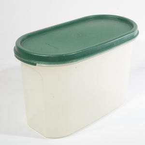 以下が含まれることがあります： 緑色の蓋が付いた透明なプラスチック製の楕円形の容器。容器は空です。