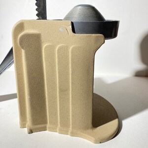 May include: A beige metal citrus juicer with a silver top and a lever. The juicer has a textured surface and a round base.