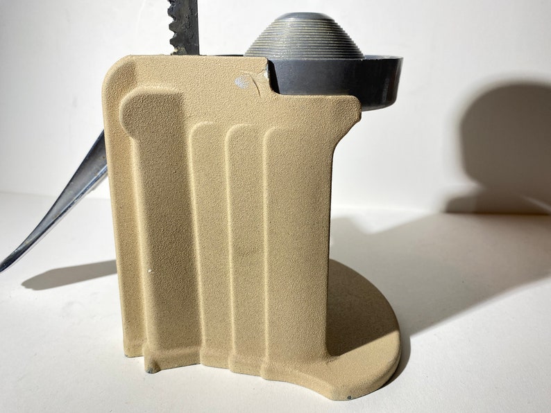 May include: A beige metal citrus juicer with a silver top and a lever. The juicer has a textured surface and a round base.