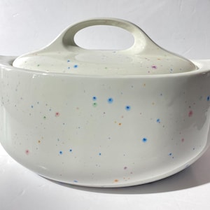 Op de afbeelding: Witte keramische ovenschaal met deksel en een gespikkeld ontwerp in blauw, groen, oranje en roze.