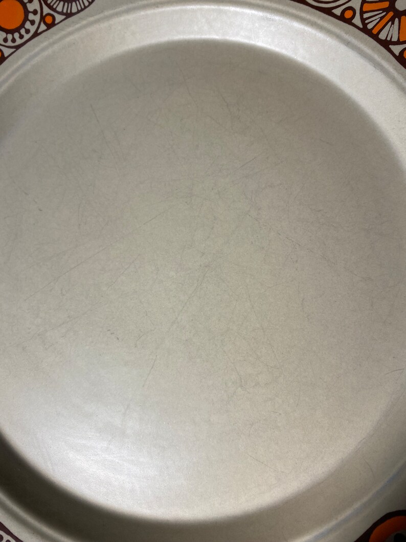 May include: A large, round, light gray serving platter with a brown and orange floral design around the rim.