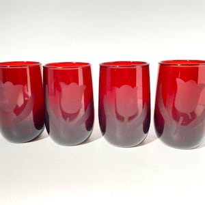 May include: A set of four stemless tumblers made of deep red glass. Each cylindrical glass features a frosted, etched design of a single tulip flower with leaves on the front surface, showcasing a smooth rim and a rounded base profile.