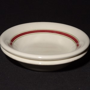 Op de afbeelding: Twee witte keramische kommen met een rood en groen streepontwerp. De kommen zijn op elkaar gestapeld.