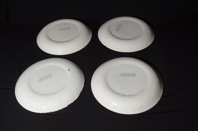May include: Four white ceramic plates with a blue and white floral design. The plates are marked "The Hawthorne Collection" on the bottom.