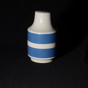 May include: A white ceramic vase with two blue stripes around the middle.