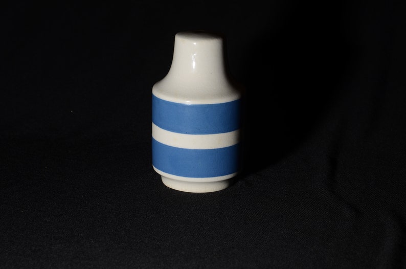 May include: A white ceramic vase with two blue stripes around the middle.