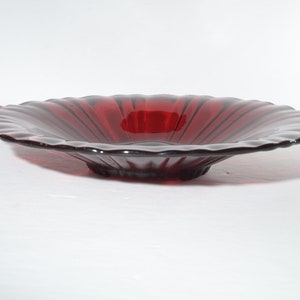 Puede incluir: Un cuenco de vidrio rojo oscuro con un borde festoneado y un diseño acanalado. El cuenco está hecho de vidrio transparente con un tinte rojo.