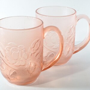 Peut inclure: Deux tasses en verre rose avec un motif floral. Les tasses ont une finition givrée et sont parfaites pour servir des boissons chaudes.