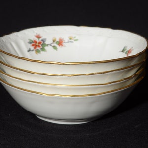 May include: Set of four white porcelain bowls with a floral design and gold trim. The bowls are stacked on top of each other.