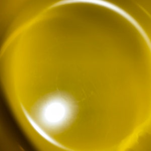 May include: A close-up of a yellow bowl with a bright white light reflecting off the surface.