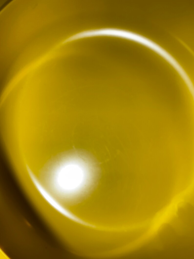 May include: A close-up of a yellow bowl with a bright white light reflecting off the surface.