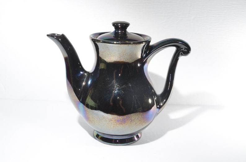 May include: A black iridescent ceramic teapot with a lid and a curved handle.