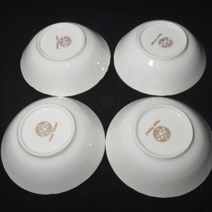 May include: Four white ceramic bowls with a gold rim and a gold logo that reads "Royal Delft" on the bottom.