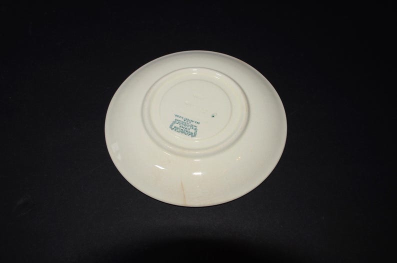 May include: White ceramic saucer with a green printed mark on the bottom that reads "Made in England, Crown Staffordshire, England".