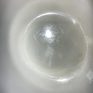 May include: A white ceramic bowl with a smooth, glossy finish. The bowl is empty and reflects light.