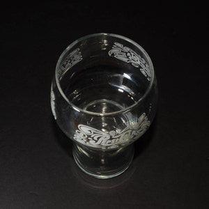 May include: A clear glass drinking glass with an etched design of the Pepsi logo and waves. The glass has a wide base and a narrow top.