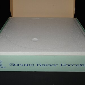 May include: A light blue box with a white foam insert and the text "Genuine Kaiser Porcelain" printed on the front. The box has a crown logo with the word "Kaiser" underneath.