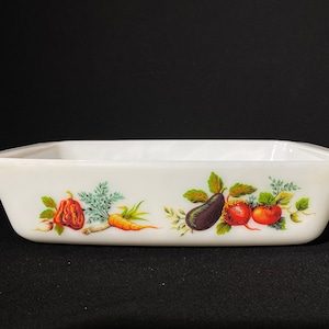 Könnte beinhalten: Weiße Keramik-Backform mit einem Blumendesign mit Gemüse wie Karotten, Paprika und Auberginen. Die Form hat einen abgerundeten Rand und eine leicht ausgestellte Lippe.