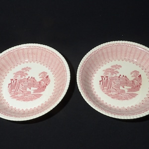 Könnte beinhalten: Zwei weiße Keramikschalen mit rosa Blumenmustern. Die Schalen haben einen gewellten Rand und einen erhöhten Rand.