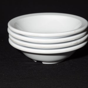 May include: Four white ceramic bowls stacked on top of each other.