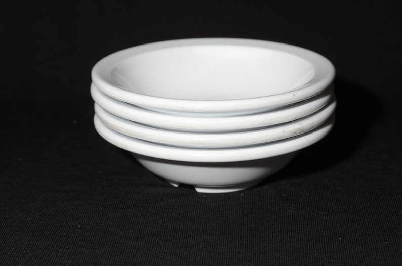 May include: Four white ceramic bowls stacked on top of each other.