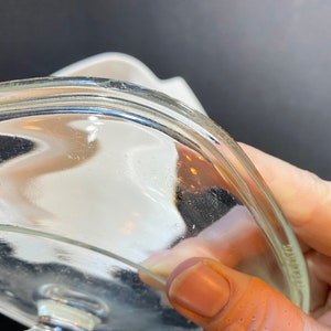 K&ouml;nnte beinhalten: Nahaufnahme der Unterseite eines durchsichtigen Glasdeckels mit leicht erh&ouml;htem Rand. Der Deckel ist leicht gew&ouml;lbt und hat eine glatte, gl&auml;nzende Oberfl&auml;che.