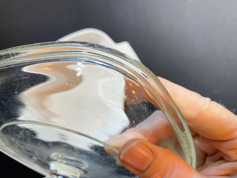 K&ouml;nnte beinhalten: Nahaufnahme der Unterseite eines durchsichtigen Glasdeckels mit leicht erh&ouml;htem Rand. Der Deckel ist leicht gew&ouml;lbt und hat eine glatte, gl&auml;nzende Oberfl&auml;che.