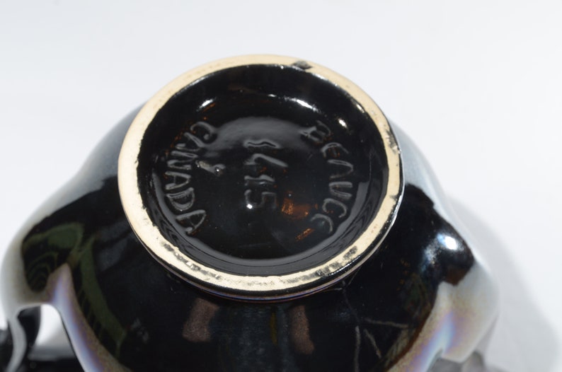 May include: Black ceramic teapot with a gold rim and the words "Renucci" and "Canada" on the bottom.