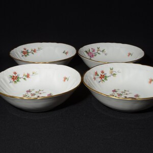 May include: Set of four white porcelain bowls with a gold rim and floral pattern. The bowls are ideal for serving soup, cereal, or dessert.