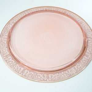 Puede incluir: Una bandeja de servir de vidrio rosa con un borde dorado y un delicado dise&ntilde;o floral grabado.