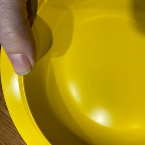 May include: A bright yellow ceramic bowl with a smooth, glossy finish. The bowl is empty and has a slightly rounded rim.