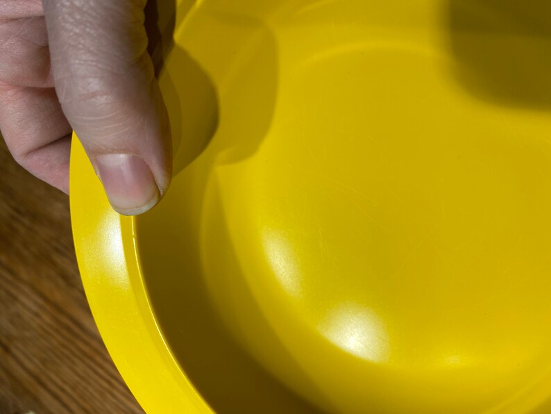 May include: A bright yellow ceramic bowl with a smooth, glossy finish. The bowl is empty and has a slightly rounded rim.