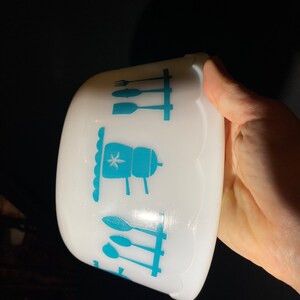 May include: White ceramic bowl with a blue and white kitchen design. The design features a stovetop, utensils, and a star.