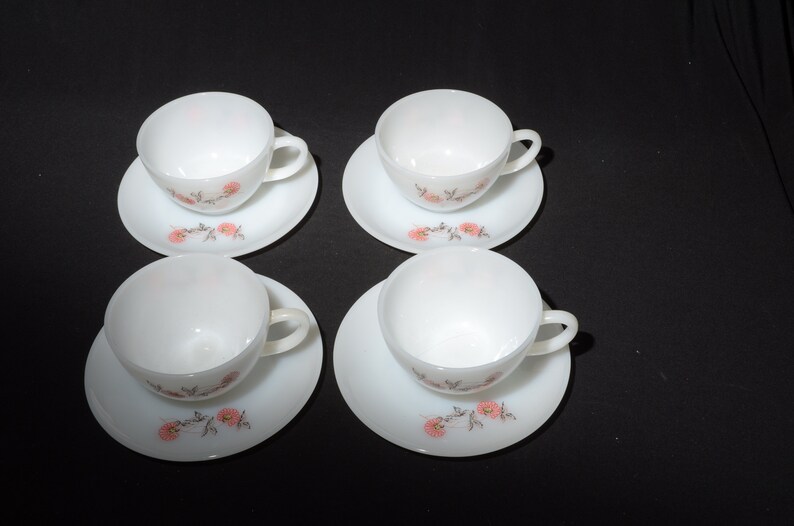 May include: Set of four white ceramic teacups and saucers with a floral design featuring pink flowers and brown stems.