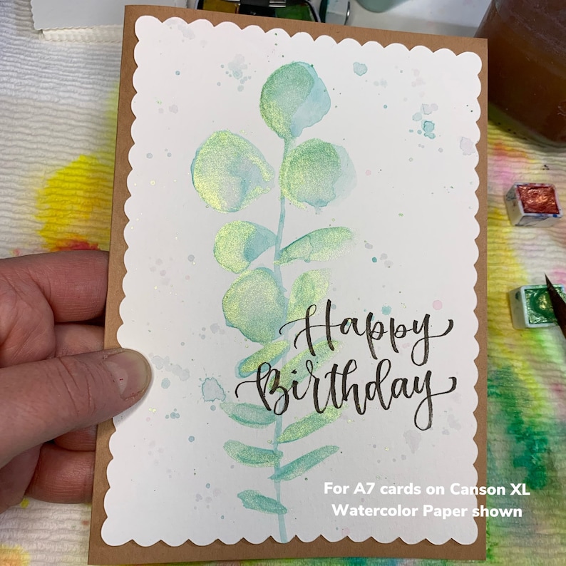 May include: A watercolor card with a green leafy design and the words "Happy Birthday" written in black ink. The card is on Canson XL Watercolor Paper.