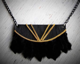May include: A black leather necklace with a gold chain trim and black feather fringe.