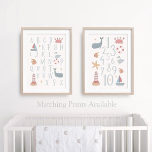 May include: Two framed prints with a nautical theme. The first print features the alphabet with a different sea creature or nautical object next to each letter. The second print features the numbers 1-10 with a different sea creature or nautical object next to each number.