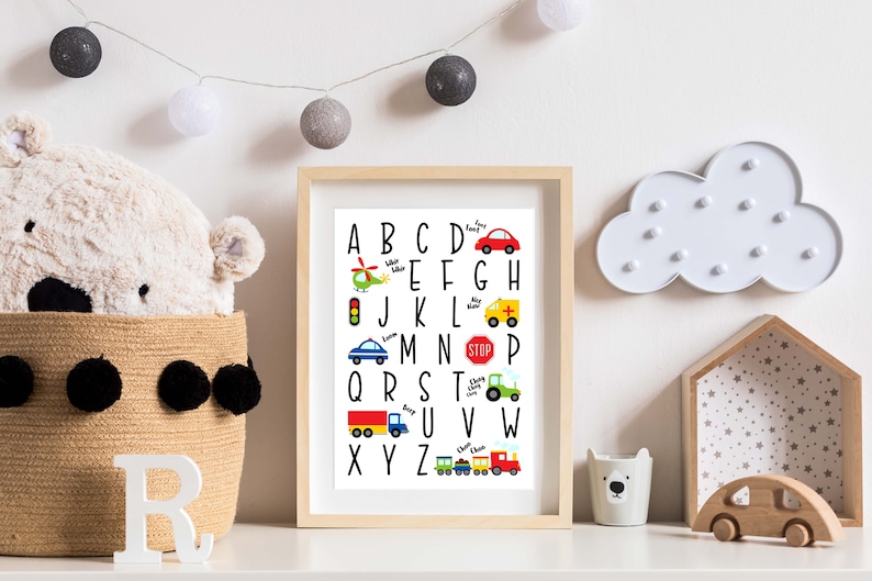 May include: A black and white alphabet chart with colorful illustrations of vehicles, including a helicopter, a car, a traffic light, an ambulance, a tractor, a truck, and a train. The letters are in uppercase and are arranged in alphabetical order.