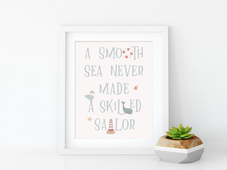 May include: A white framed print with a light pink background and blue text that reads "A smooth sea never made a skilled sailor". The print features nautical illustrations including a seagull, a whale, a life preserver, a starfish, and a lighthouse.